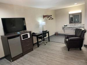 LittlefieldCrescent Park Motel & Suites的酒店客房设有电视、椅子和书桌