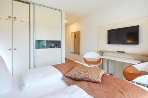 NeuensteinVR-Serviced Apartments Obergeis的卧室配有一张床铺,墙上配有电视