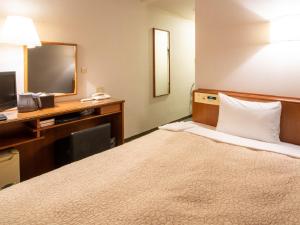 湖西市库尔泰克 －滨名湖旅馆的酒店客房配有一张床、一张书桌和一台电视。
