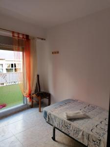 瓦伦西亚PISO EN MALVARROSA的一间卧室设有一张床、一个窗口和一把椅子