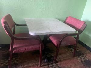 Donalsonville塞米诺尔酒店的一张桌子、两把粉红色的椅子和一张白色的大理石桌子及椅子
