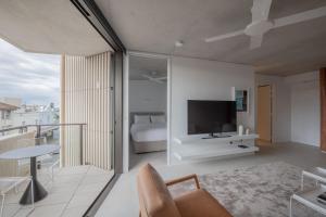 悉尼Hotel Ravesis的客厅设有床铺和墙上的电视