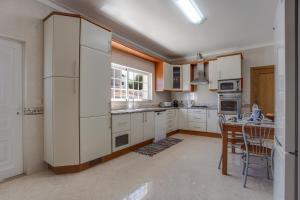 Senhora do VerdeCasa Village的厨房配有白色橱柜和桌子