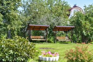 别洛库里哈Отель "Белокуриха"的两长椅,在院子里放着树木和鲜花