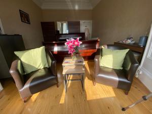 奥本Ardmhor Guest House的客厅配有两把椅子和一张鲜花桌子