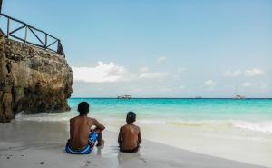 南威Amaan Beach Bungalows的坐在海滩上看海洋的两个人