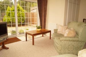 East AnsteyEdge of Exmoor Garden Flat, dog friendly, sleeps 2 - 4的带沙发、桌子和电视的客厅