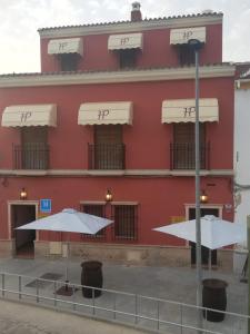 Huévar佩奇旅馆的一座红色的建筑,前面有两把伞