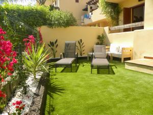 维拉Bahia Marinas - Tu hogar con jardín privado!的后院,带椅子和草,鲜花