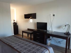 弗吉尼亚海滩旅行者湾海滩酒店的一间卧室配有一张桌子和一张带电视的床。