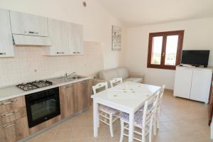 布多尼Corte di Gallura的厨房配有桌子和白色的桌椅