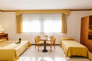 瓦伦扎诺Hotel Residence Federiciano的酒店客房设有两张床和一张桌子。