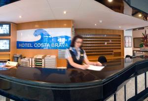 滨海托萨GHT克斯塔布艾瓦&Spa水疗酒店的坐在酒店赌场药房柜台的男人