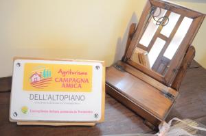 SerleAgriturismo dell'Altopiano的坐在一张桌子上的标志,就在一扇敞开的门旁边