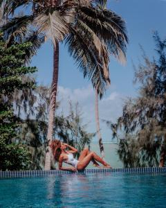 雅帕拉廷加Vila de Taipa Exclusive Hotel的两个女人躺在棕榈树游泳池边