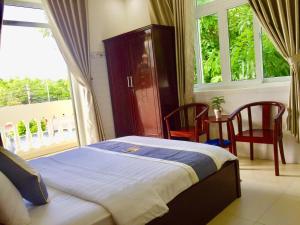 昆岛Khách Sạn Minh Thắng的一间卧室配有一张床、两把椅子和一个窗户