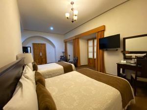 萨卡特卡斯Hotel Casa Faroles Centro Histórico的酒店客房设有两张床和电视。