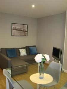 桑坦德Apartamentos La Pereda Santander- Estudio E1的客厅配有沙发和鲜花桌