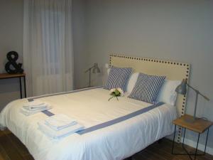 桑坦德Apartamentos La Pereda Santander- Estudio E1的一张铺有白色床单的床,上面有花