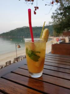 沙拉海滩沙拉德小屋酒店的坐在海滩旁的桌子上喝着红草
