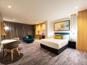 堪培拉Mercure Canberra Belconnen的配有一张床和一张书桌的酒店客房
