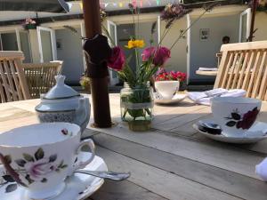 东考斯阿尔伯特别墅乡村民宿的一张木桌,上面放有盘子和杯子,花朵