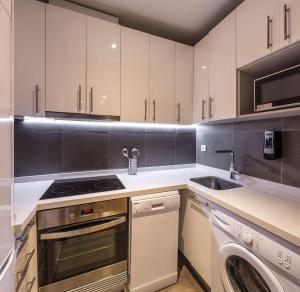 瓦伦西亚Mon Suites Catedral的厨房配有白色橱柜、洗衣机和水槽