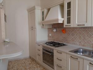 卡波利韦里APPARTAMENTO CASA MARCO的厨房配有白色橱柜、水槽和炉灶。