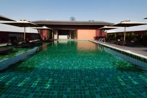 曼谷Casa Nithra Bangkok的一个带绿水和遮阳伞的游泳池