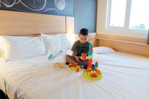 阿雷格里港Ibis Porto Alegre Assis Brasil的一只小男孩坐在床上,带着玩具