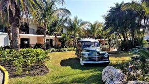 霍姆斯海滩Bali Hai Beachfront Resort and Spa的一座老车停在一个棕榈树庭院里
