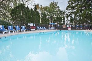 沃伦Holiday Inn Express Detroit-Warren/General Motors Technology Center, an IHG Hotel的一个带蓝色椅子和桌子的大型游泳池