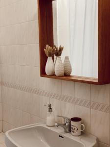 圣佩罗德姆Casa dos Pinheiros的浴室水槽,在架子上装有镜子和花瓶
