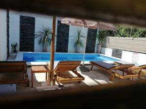 扎达尔Apartment Rustica Zadar with exclusive use of the pool-ground floor的一个带椅子和遮阳伞的庭院和一个游泳池