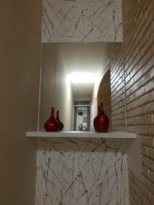 索罗卡巴HOTEL CASTELINHO DE SOROCABA的三个红色花瓶坐在浴室的架子上