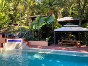 凯恩斯Cairns Rainforest Retreat的一个带桌子和凉亭的游泳池