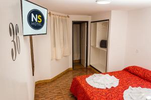 特尔马斯德里奥翁多Ns Hotel的卧室配有红色的床和墙上的标志
