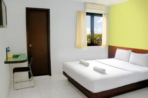 安汶LeGreen Suite Ratulangi的卧室配有白色的床和窗户。