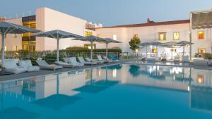 埃武拉马尔德尔阿克度托酒店的一座带椅子和遮阳伞的游泳池位于一座建筑旁边