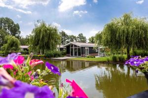 利赫滕福德TopParken – Résidence Lichtenvoorde的一座房子前面有池塘和鲜花