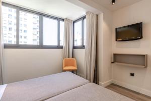 马拉加宙斯酒店的一间卧室配有一张床和一台平面电视