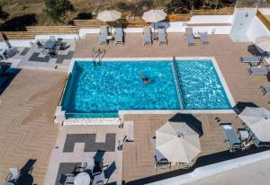 波托什Studios Apartments Irini Patira的游泳池的顶部景色,泳池里摆放着椅子,有人在泳池里游泳