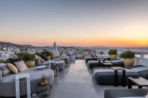 米克诺斯城The TownHouse Mykonos的酒店屋顶设有沙发和桌子,享有日落美景。