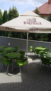SukoróDomb Apartmanok的一组绿色的桌椅,放在伞下