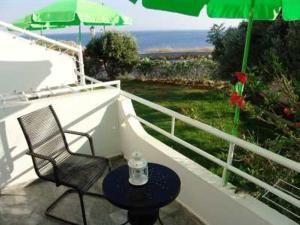 巴特斯欧Elpida Andros的阳台配有椅子、桌子和雨伞。