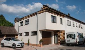 NeuweilerHochwertige und moderne Ferienwohnung Huber的停在房子前面的白色汽车