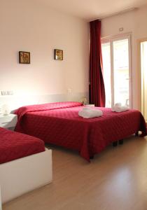 里米尼Hotel Morolli的一间卧室设有两张带红色床单的床和窗户。