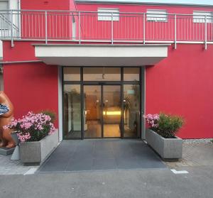 辛根Hotel Da Sabino的一座红色的建筑,有玻璃门和鲜花