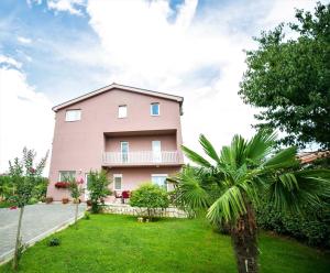 默主歌耶APARTMANI M&J Međugorje的一座带绿色庭院的大型粉红色房子