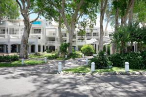 棕榈湾胡椒海滨俱乐部及水疗中心的前面有树木的白色大建筑